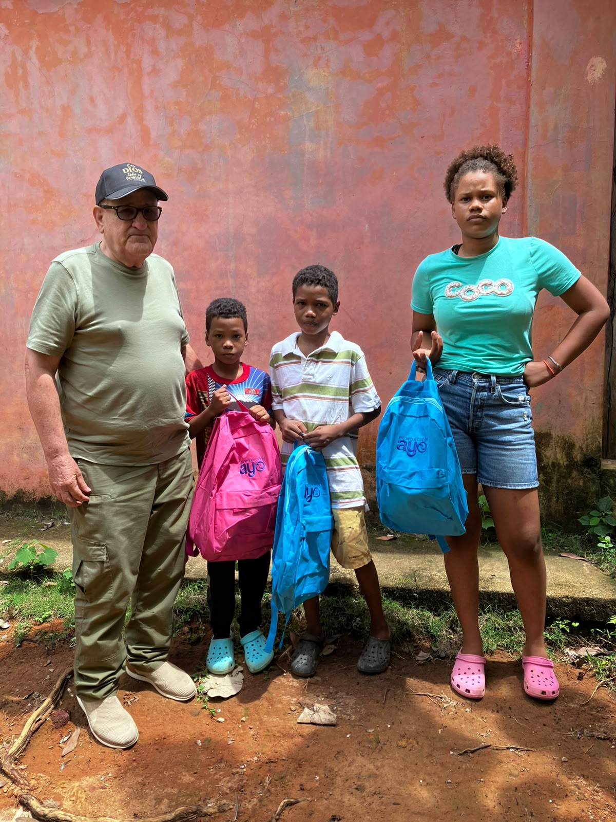 El pastor Castillo junto a tres niños de Bomba de Yaiba que acaban de recibir sus mochilas